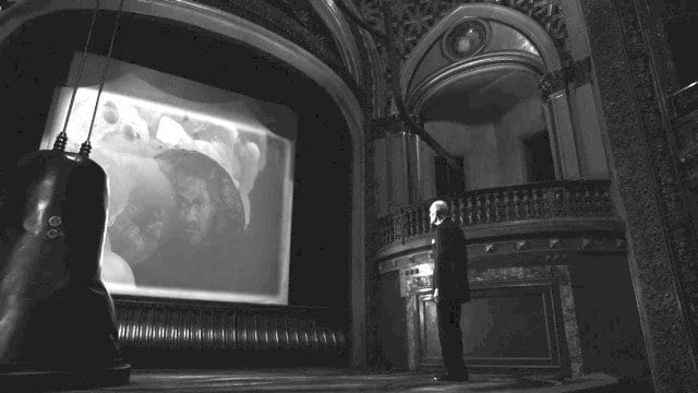 The Fireman watches a screen in a black and white theater