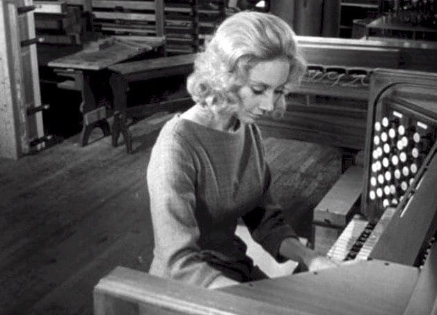 a blonde woman plays an organ in carnival of souls