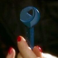 The blue key held in a woman's hand, with red nail polish
