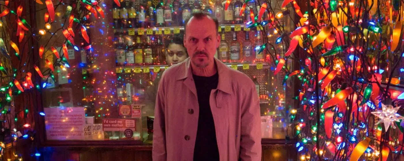 Michael Keaton stands in front of bright lights at a liquor store in Birdman