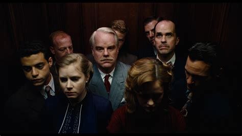 a group of people stand silently in an elevator in The Master