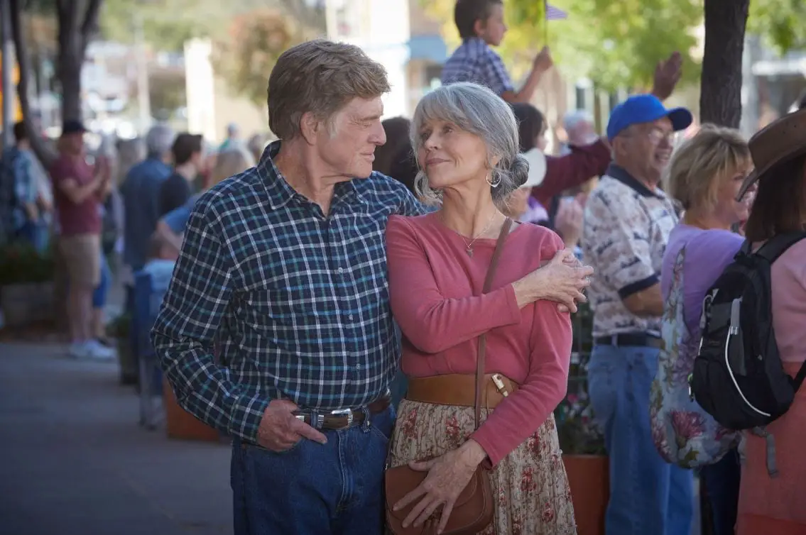 Robert Redford and Jane Fonda walk arm in arm down a street