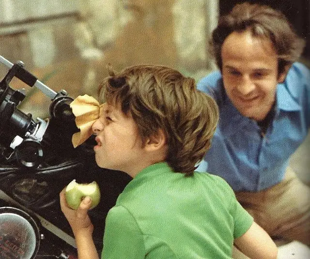 Truffaut with a boy looking through a telescope while eating an apple