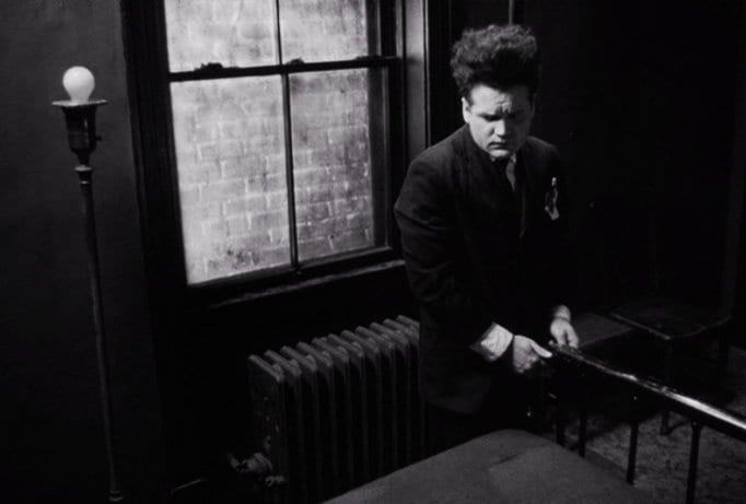 Henry Spencer looks nervously towards a bed in Eraserhead