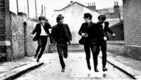 The Beatles running down a street