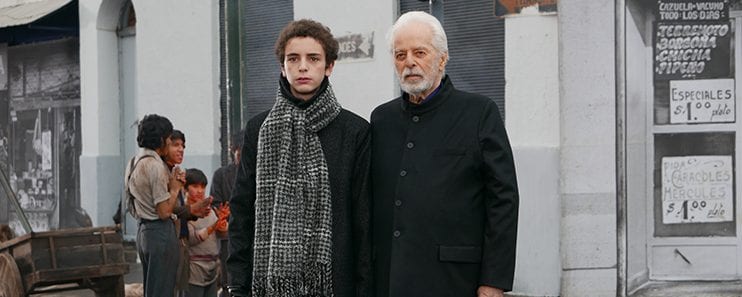 A young man and an old man stand next to each other outside a shop