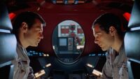 Astronauts look at each other in front of an oval window in 2001