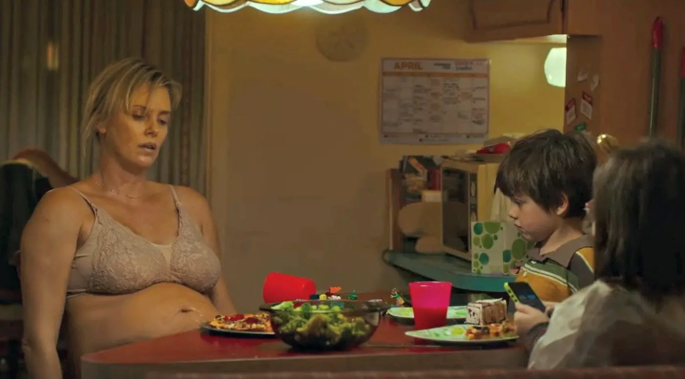 Heavily pregnant Charlize Theron sits a the dinner table with her two children in Tully