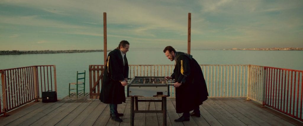 Marco Giallini and Jerzy Stuhr play table football on a deck overlooking the sea