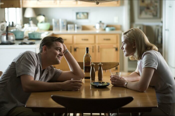 leonardo dicaprio kate winslet man and woman sitting across table from one another talking and drinking and smiling