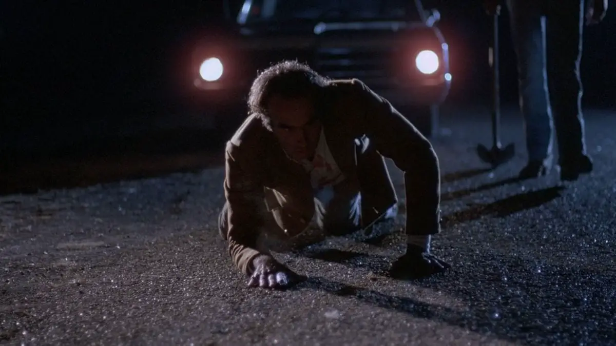 Marty (Dan Hedaya) crawls away from Ray (John Getz) and his shovel. 