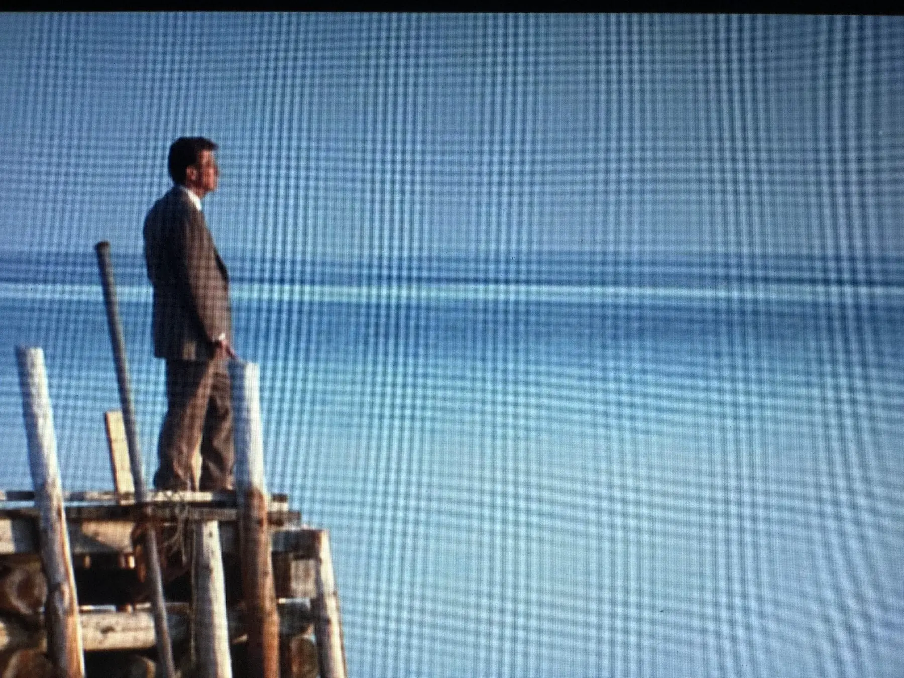 Giles stands on a pier, looking out over the ocean