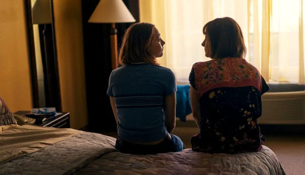 Lady Bird and her mom sit on a bed talking