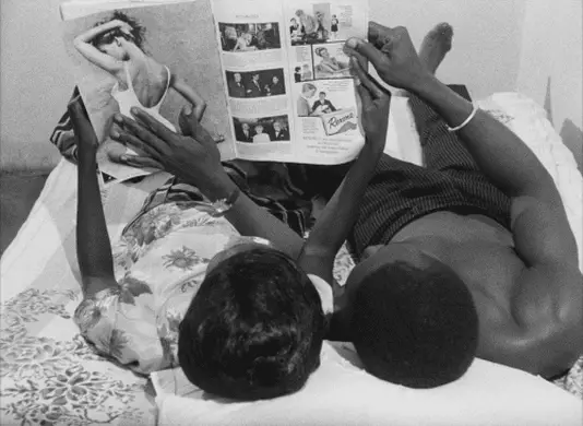 A couple in Dakar, Senegal in the 1960s look at a French magazine