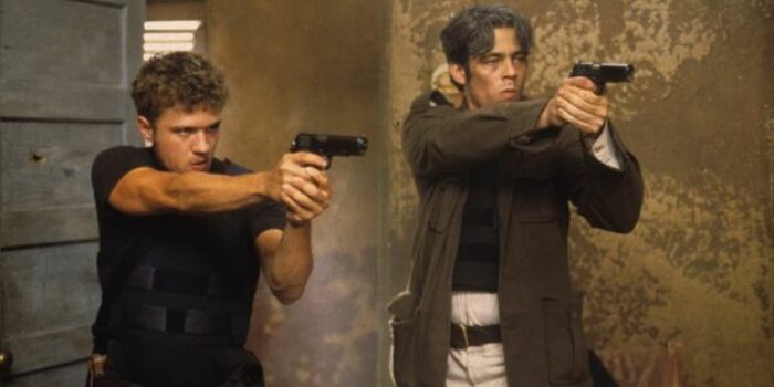 The two main characters point their guns at an unseen off-camera target