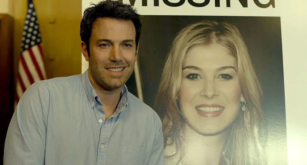 nick smiles in front of missing poster