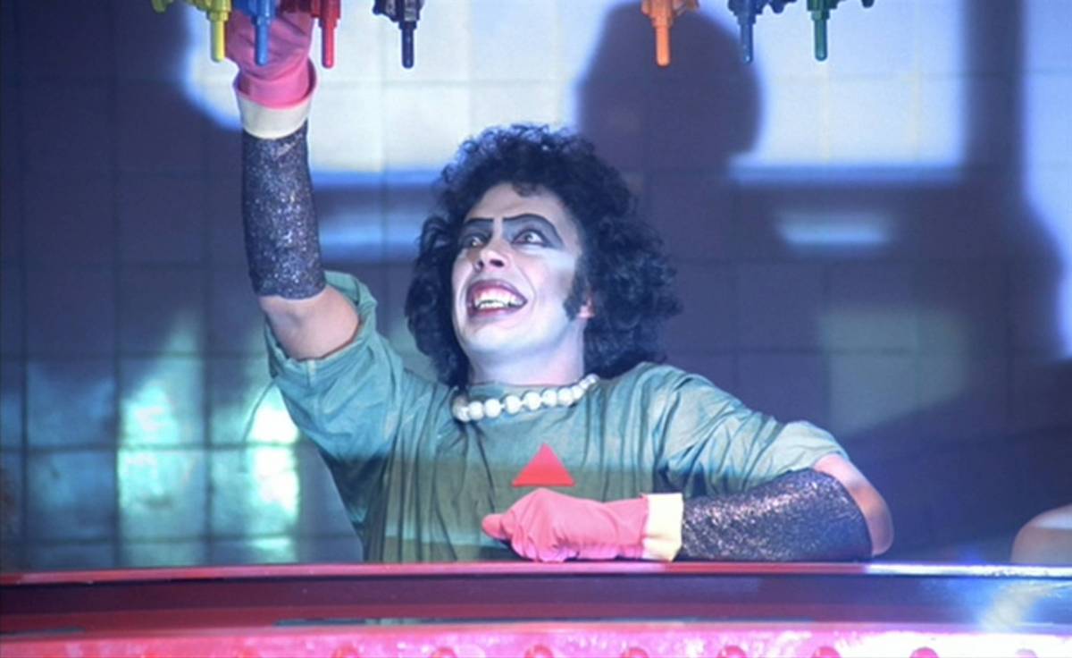 Frank-N-Furter fiddles with lab equipment to bring Rocky to life.
