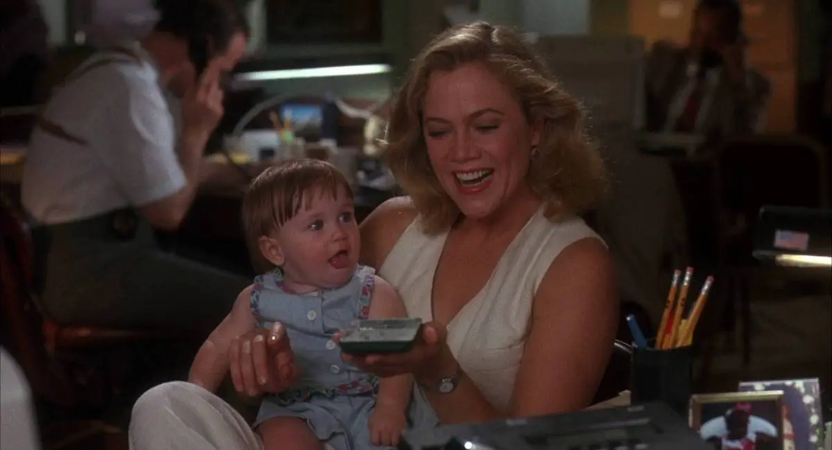 Jane holds her baby daughter while she laughs at a hand-held game in her other hand.