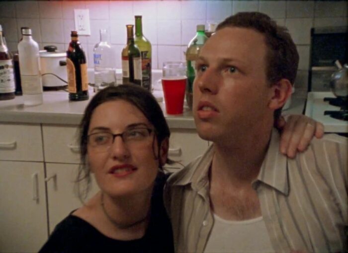 Rachel has her arm over her boyfriend Dave's shoulder at a party in Funny Ha Ha.