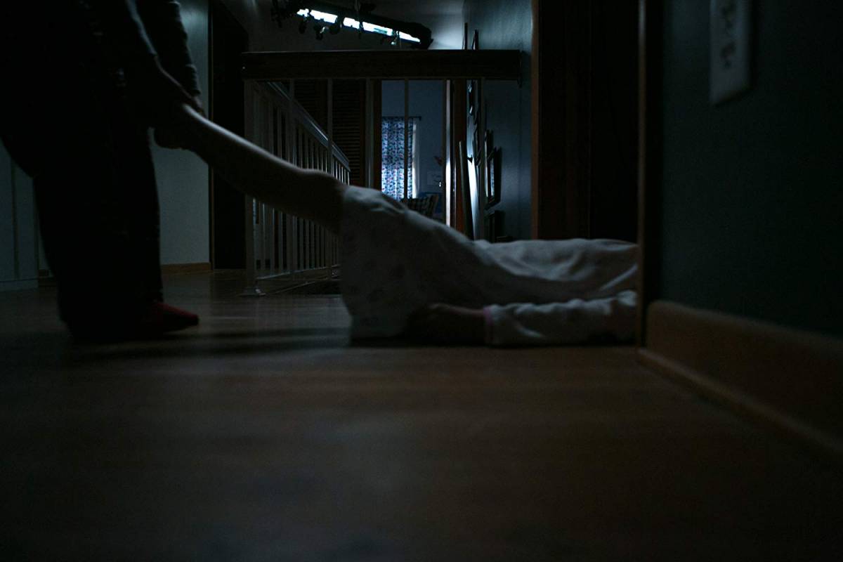 Emelie dragging a body across a a hallway