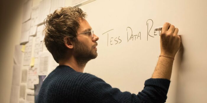 Professor Isaac Bruno (Adams) explains the TESS project on a classroom whiteboard.