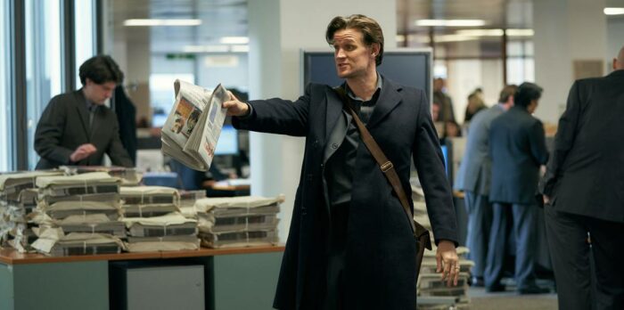 Journalist Martin Bright (Matt Smith) holds up a newspaper in the editors office
