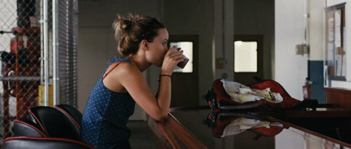 Kate (Olivia Wilde) takes a sip of a beer in her workplace lounge.