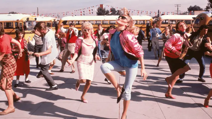 The Pink Ladies, lead by Stephanie ((Michelle Pfeiffer) dance outside school in the opening number "Back to School" in Grease 2.