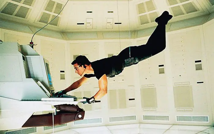 Hunt suspended from the ceiling by wires, operating a computer