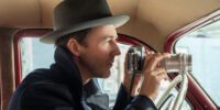 Lionel Essrog (Edward Norton) lines up his camera to shoot a person of interest from the front seat of his car.