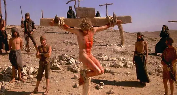 Jesus hangs from a cross bleeding naked wsurrounded by Roman guards