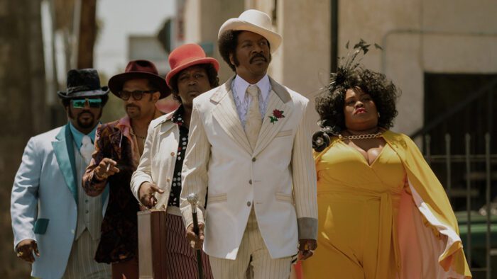 Rudy Ray Moore and his associates walk down the street dressed sharply