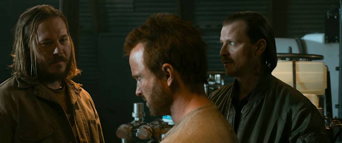 Neil and Kenny stand on either side of Jesse as they make a bet over whether he can break the rig in the meth lab