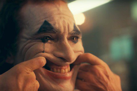 Joker paints his face like a clown and lifts his lips to a grin