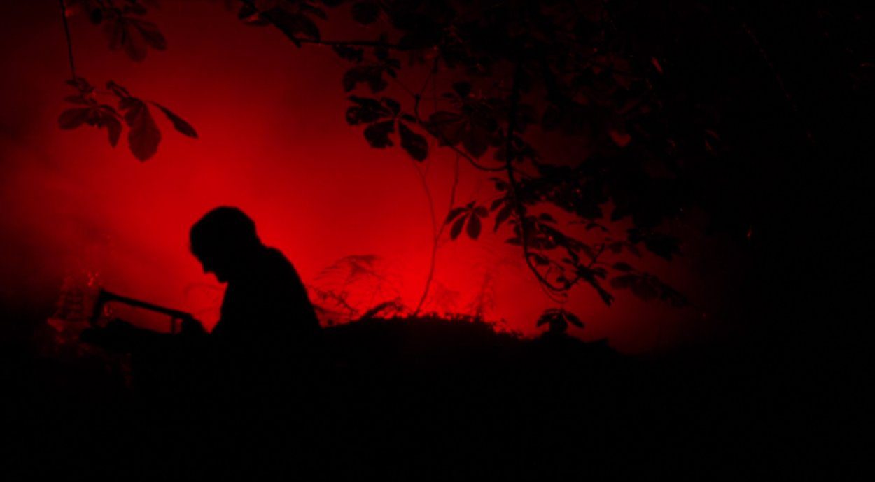 Graveside silhouette of a figure against a red background