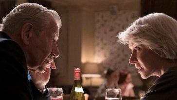 Ian McKellen and Helen Mirren speak with each other closely at a dinner table in The Good Liar