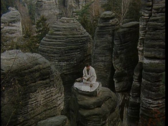 Faust stands on a rock tower as he tries to summon the devil