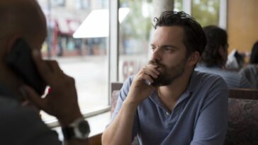 Eddie (Jake Johnson) peers out the window to ponder while inside a diner