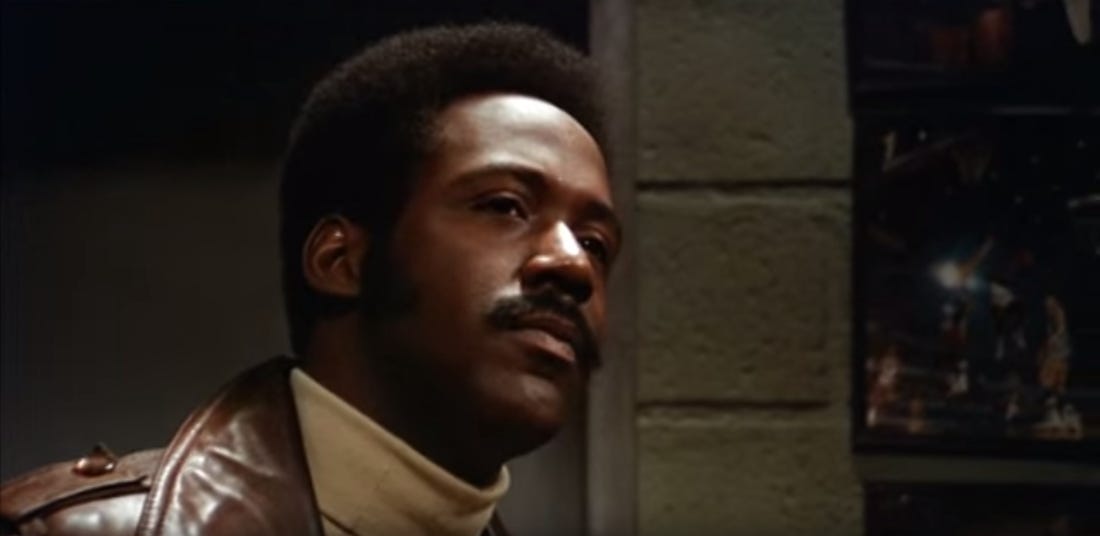 John Shaft (Richard Roundtree) is staring off intot he distance looking thoughtful.