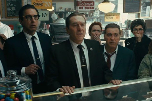 Ray Romano, Robert De Niro and Al Pacino staring at a TV screen behind a deli counter in The Irishman