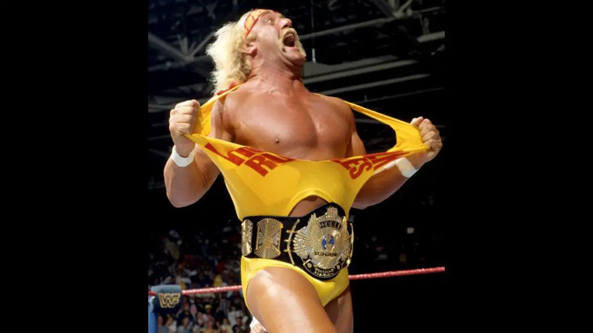Hulk Hogan stands in a wrestling ring, tearing his T-shirt apart