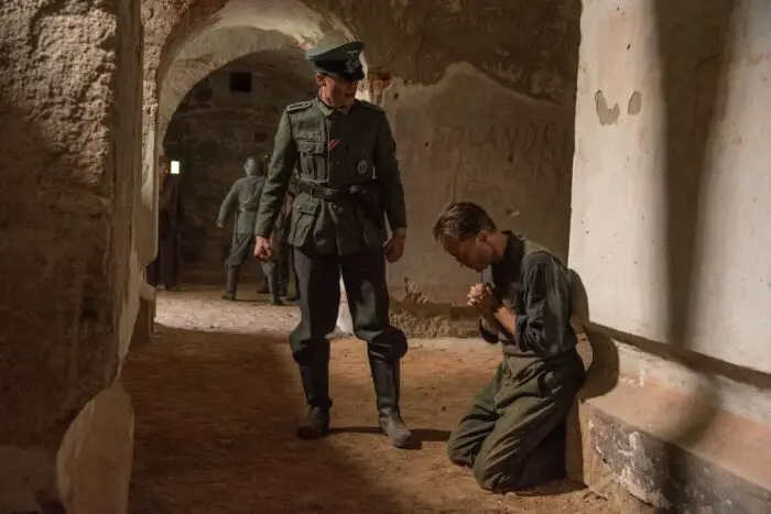 Franz kneels to pray while being interrogated by a Nazi officer