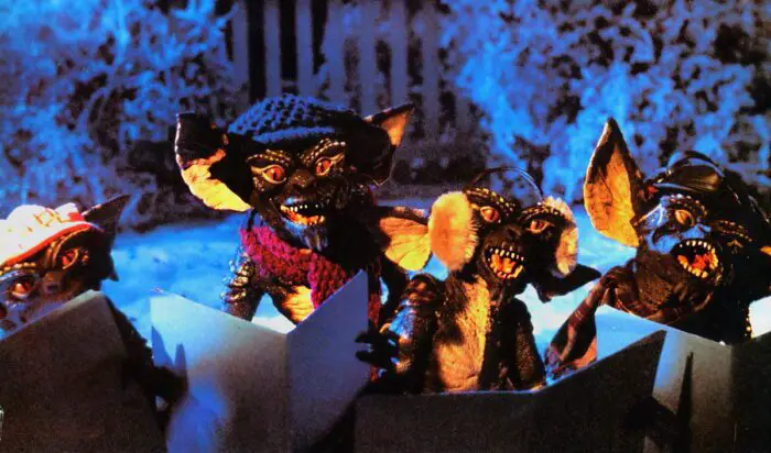 Stripe and his fellow evil Gremlins ssing Christmas carols outside Mrs. Deagel's house