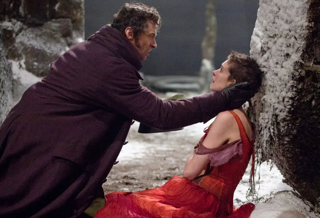Fantine lies in the street, Valjean kneels down to help her