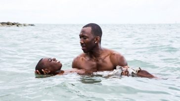 A man helps a boy swim in the ocean