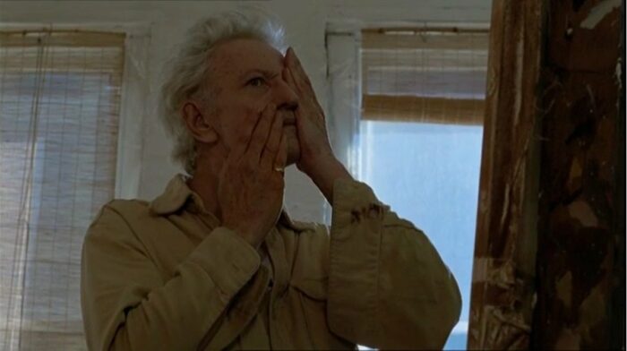 Nicholas Ray as Derwatt touching his face