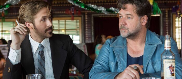 Ryan Gosling smokes a cigarette while staring at a distraught Russell Crowe at a bar