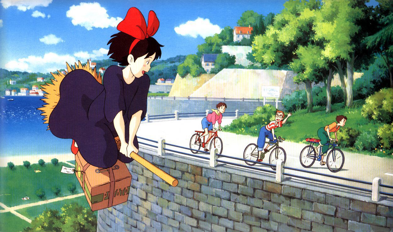 Kiki flies on her broom alongside Tombo and his friends on bikes
