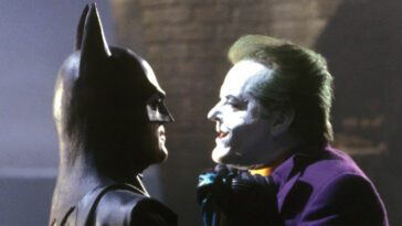 Batman holds Joker close to his face by the scruff of his neck