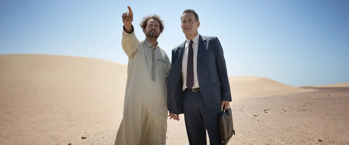alan clay standing in the desert with his driver, yousef who is pointing into the distance